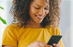 Foto de uma jovem mulher sorridente olhando para o celular