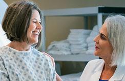 Foto de uma médica olhando para uma paciente sorridente
